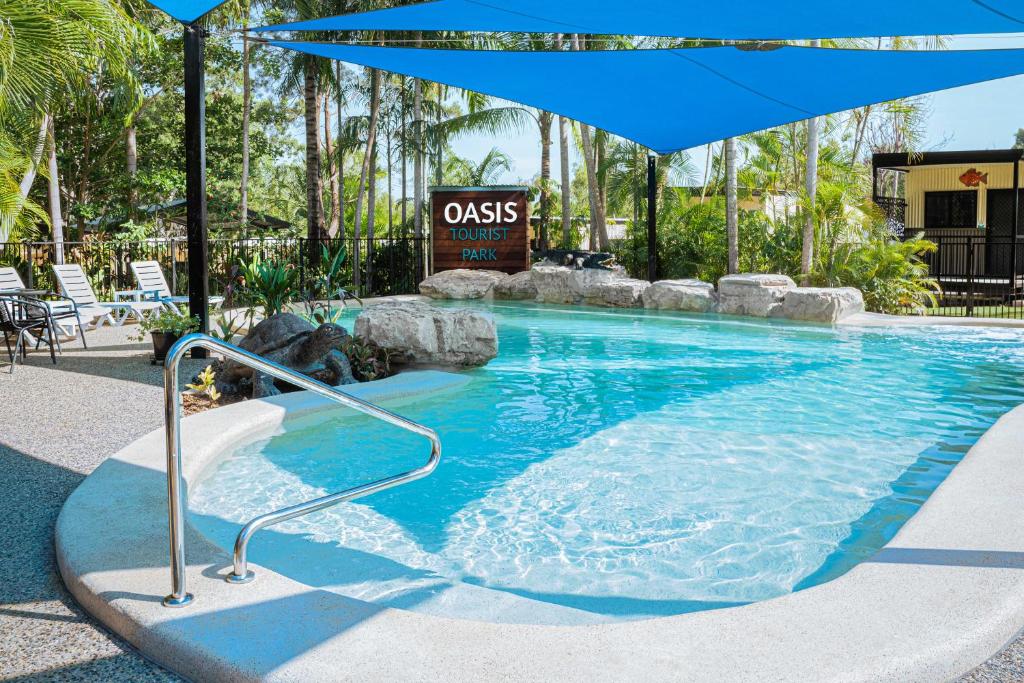 a swimming pool with an umbrella in a resort at Oasis Tourist Park in Palmerston