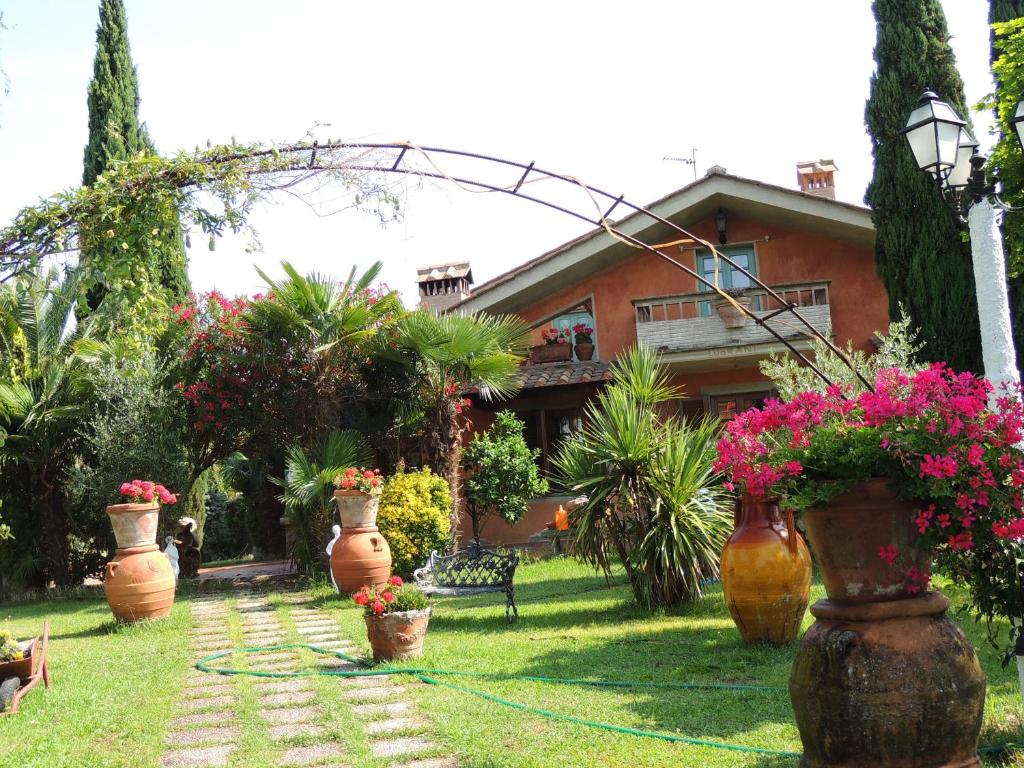 a garden with several large pots of flowers in front of a house at Il Cipresso del Gallo in Montecatini Terme