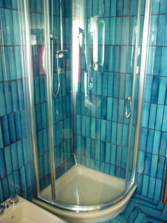 a shower in a bathroom with blue tiles at B&B Cà d'Artisti in Caorle