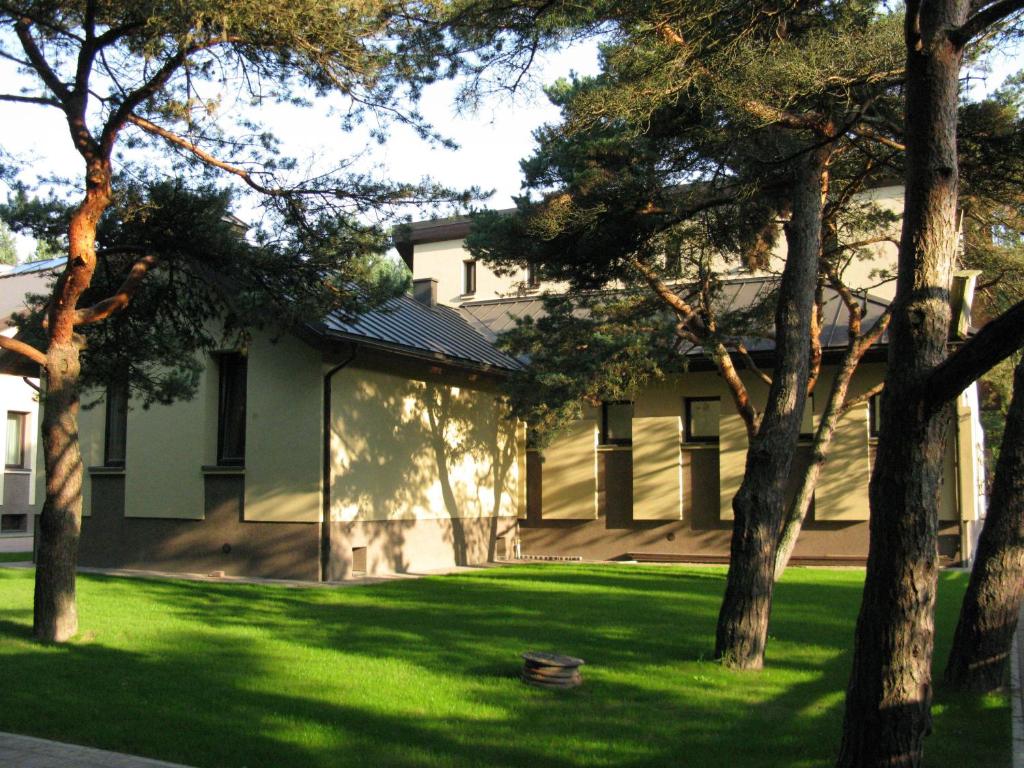 un edificio con un patio con césped verde y árboles en Uzkanaves 15, en Palanga