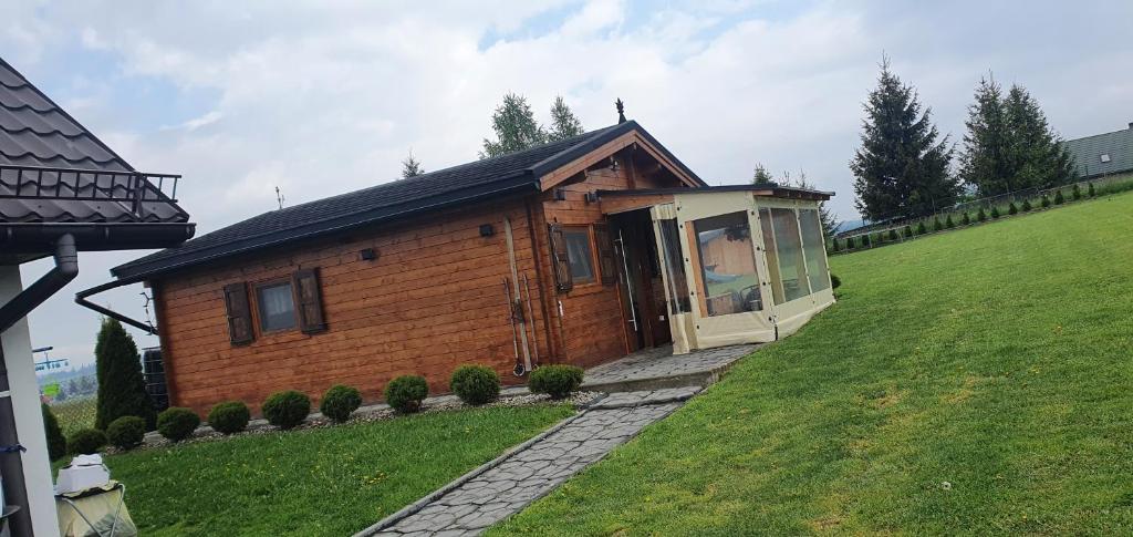 uma pequena cabana de madeira numa colina relvada em Domek drewniany em Piekielnik