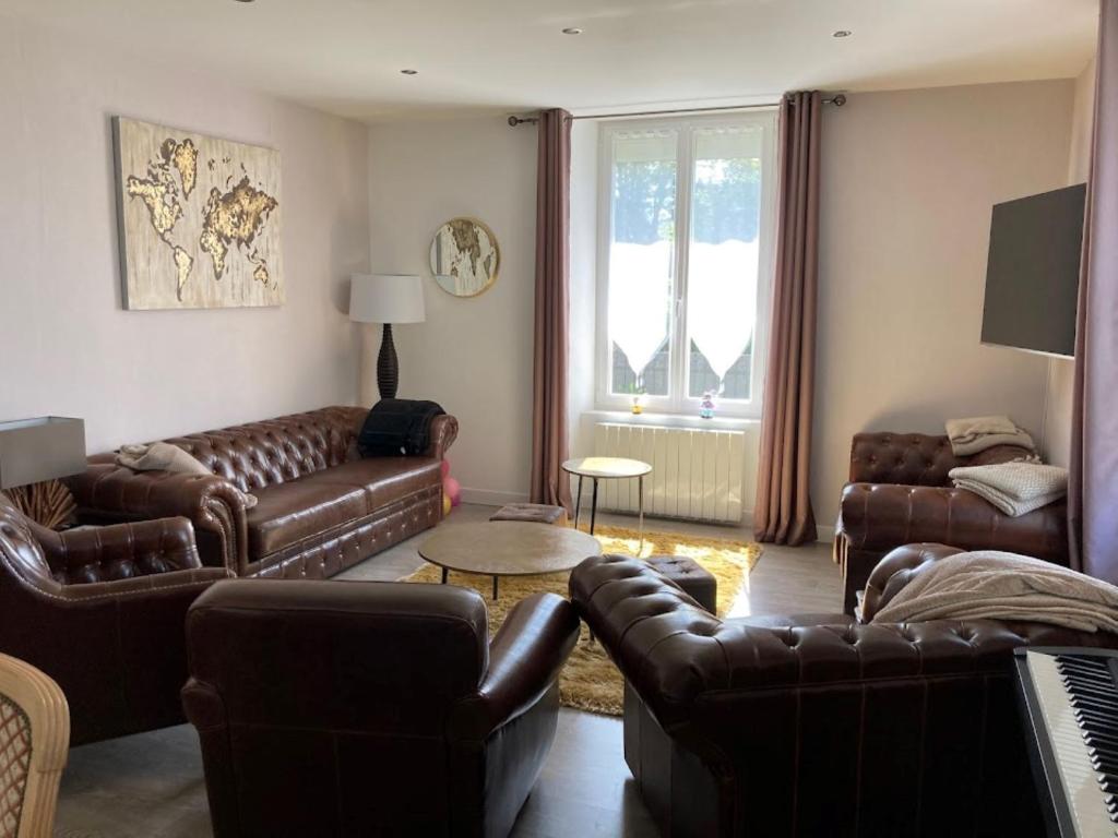 Elle comprend un salon doté d'un mobilier en cuir brun et d'une fenêtre. dans l'établissement Gite de Luxe Hautes Vosges Chez Livia, à Bruyères