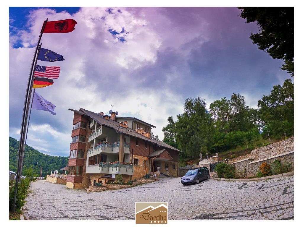 a building with flags and a car parked next to it at Hotel Dardha in Dardhë