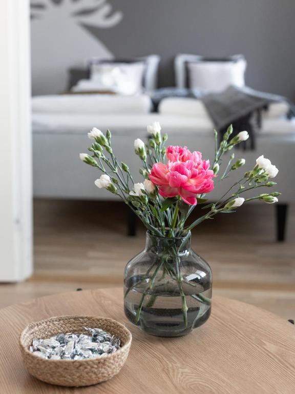 a glass vase with pink flowers on a table at Arctic Railway City Suite in Rovaniemi