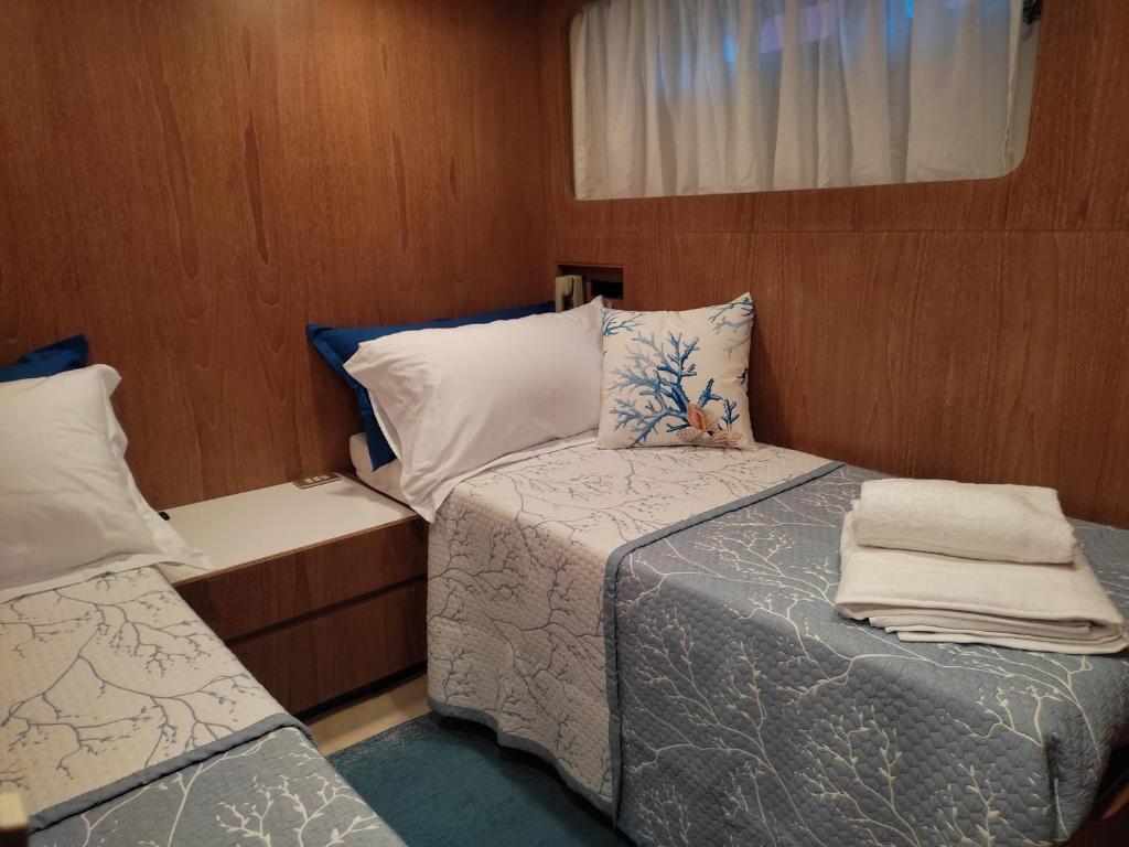a small bedroom with two beds and a window at BOAT & BREAKFAST LUCRETIA, LUXURY yacht in Àrbatax