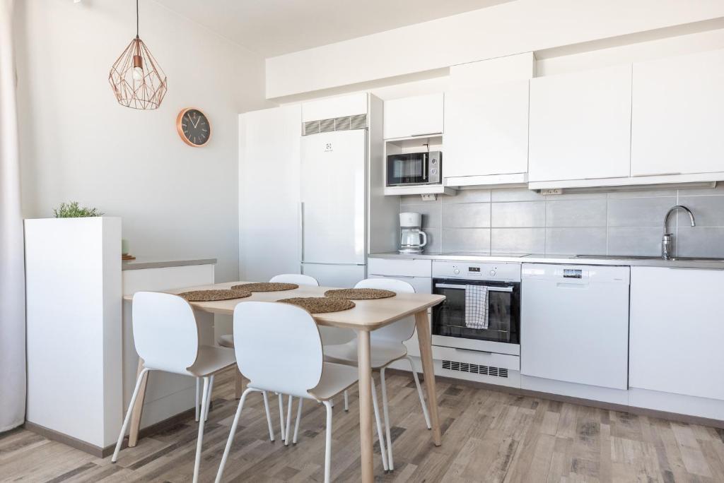 a kitchen with white cabinets and a table and chairs at Arctic Penthouse City Suite in Rovaniemi
