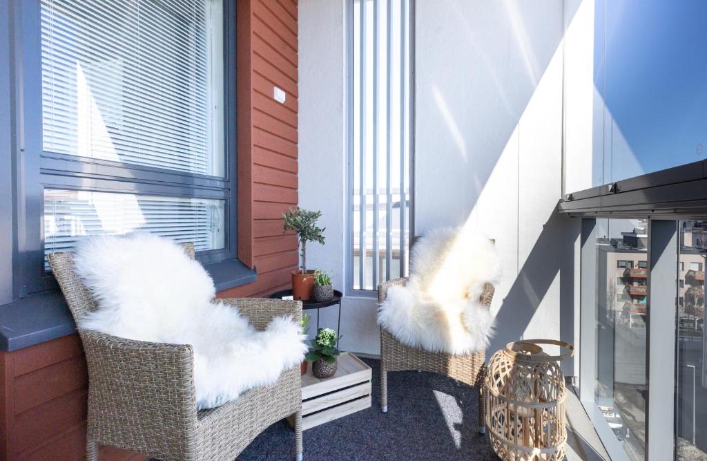 two wicker chairs with white fluffy cushions on a balcony at Arctic Penthouse City Suite in Rovaniemi