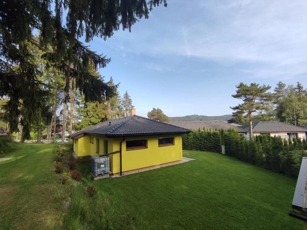 a yellow house in the middle of a yard at Sunny House in Lipno nad Vltavou