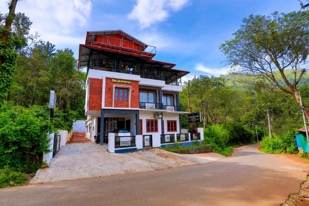 ThirunelliにあるDakshinakasi Guest Houseの道路脇の高い赤白の建物