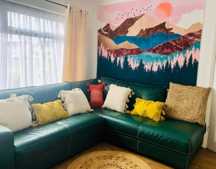 a green couch with colorful pillows in a living room at 10 Minutes Walk To The Beach in Port Talbot