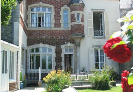 una gran casa de ladrillo con una flor roja delante de ella en La Demeure de Laclais en Le Mans