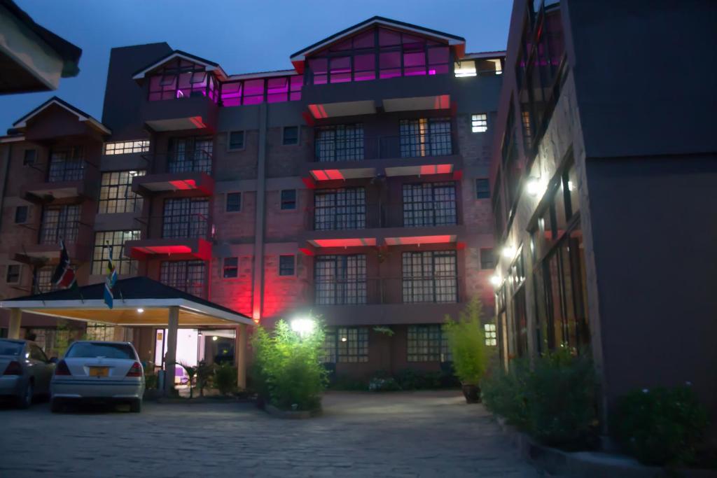 a tall building with a parking lot in front of it at 67 Airport Hotel Nairobi in Nairobi