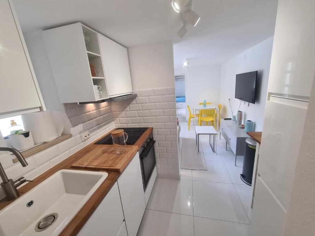 uma cozinha branca com um lavatório e uma mesa em Apartment Summer Joy em Supetar