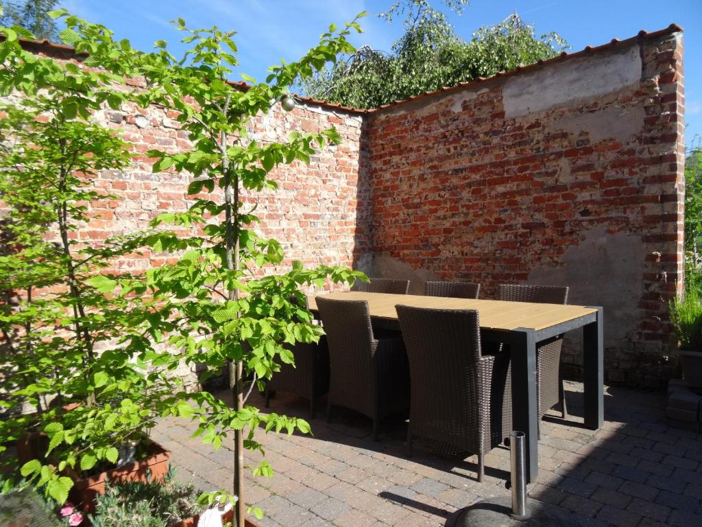 una mesa y sillas en un jardín con una pared de ladrillo en Maison Miest, en Watou