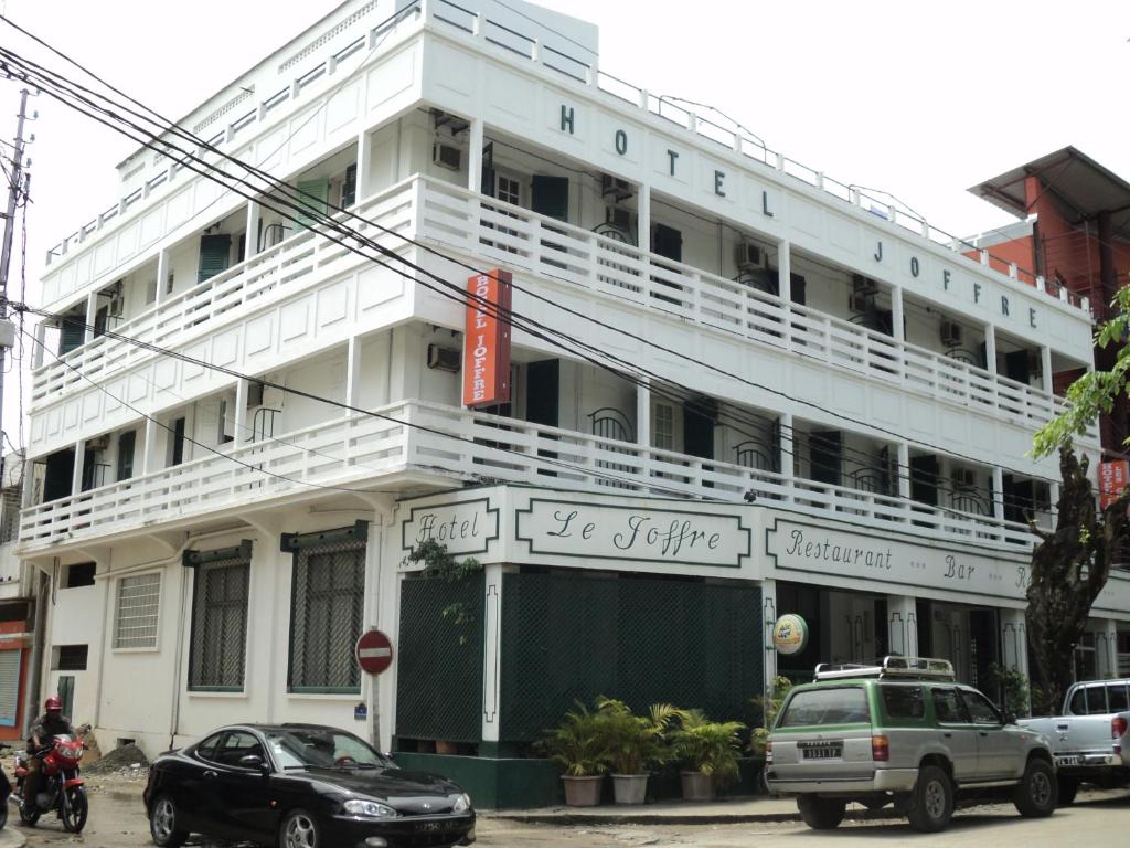 un edificio blanco con coches estacionados frente a él en Hotel Joffre, en Toamasina