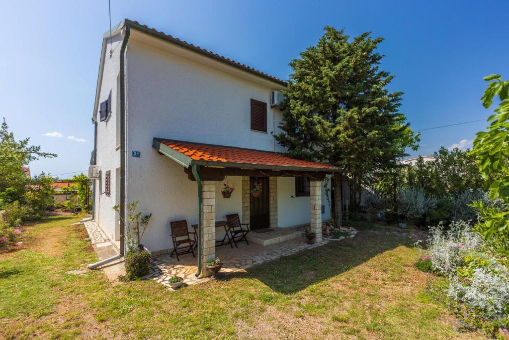 a small white house with a table and chairs at Apartment Kreso in Punat