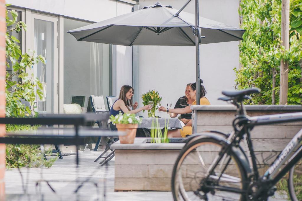 zwei Frauen, die an einem Tisch unter einem Schirm sitzen in der Unterkunft Het Oplaadpunt: bed, bike, hike, 8-12 p. in Diksmuide