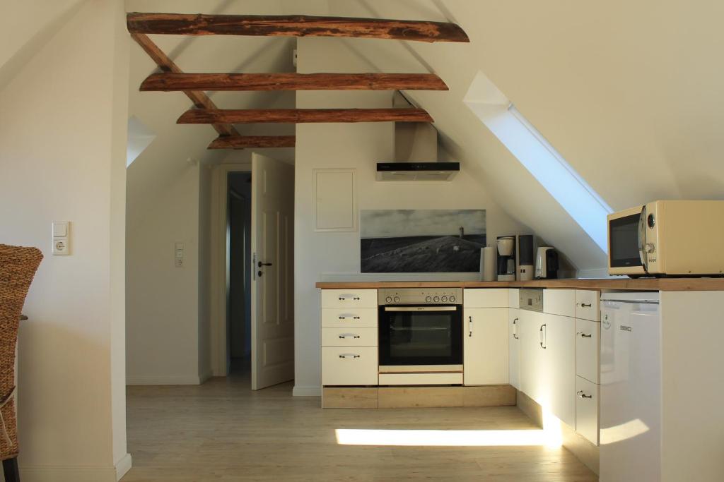 une cuisine avec des armoires blanches et un toit dans l'établissement Elske´s Stuuv, à Krummhörn