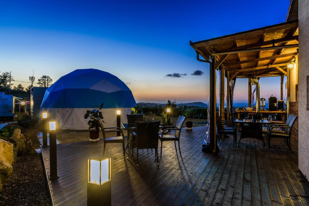 a patio with tables and chairs and an umbrella at Jeju Starlight Glamping in Jeju