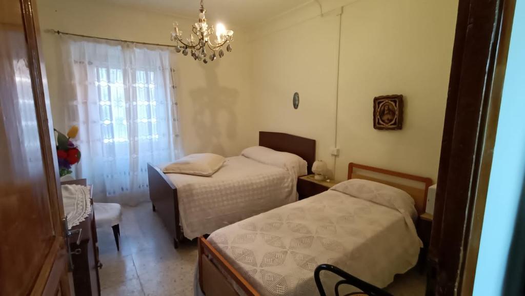 Habitación pequeña con 2 camas y lámpara de araña. en Casa vacanze a Furci (Chieti), en Furci
