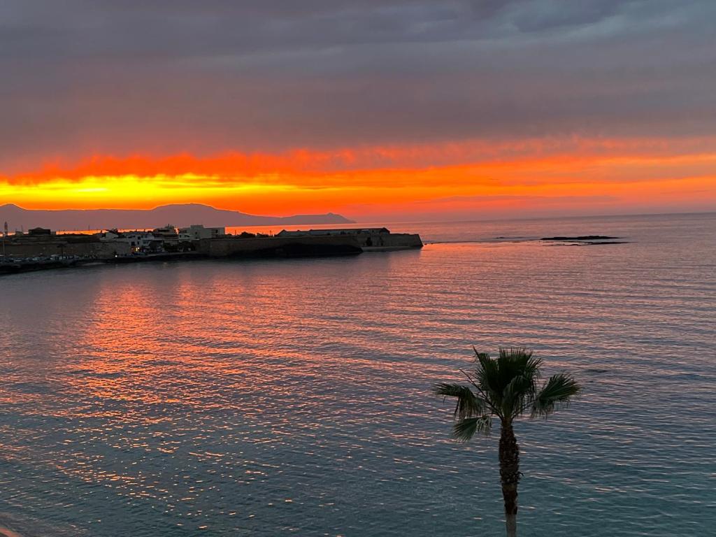 un coucher de soleil sur l'océan avec un palmier dans l'établissement Zonapartments B sea view- city center, à La Canée