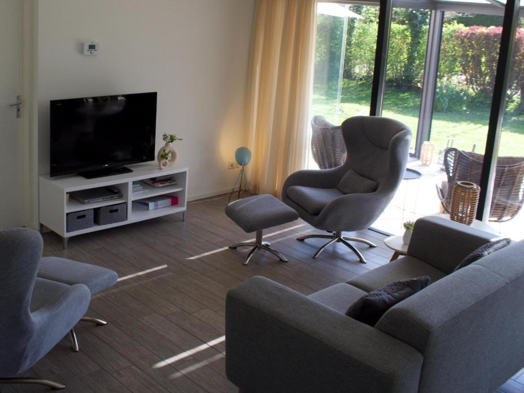 ein Wohnzimmer mit Sofa, Sesseln und Fernseher in der Unterkunft Bungalow near Veerse Meer with Private Garden in Kamperland