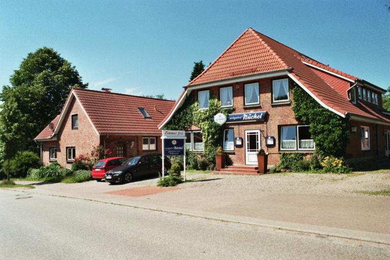 ein Gebäude mit einem davor geparkt in der Unterkunft Landgasthof Nüchel in Malente