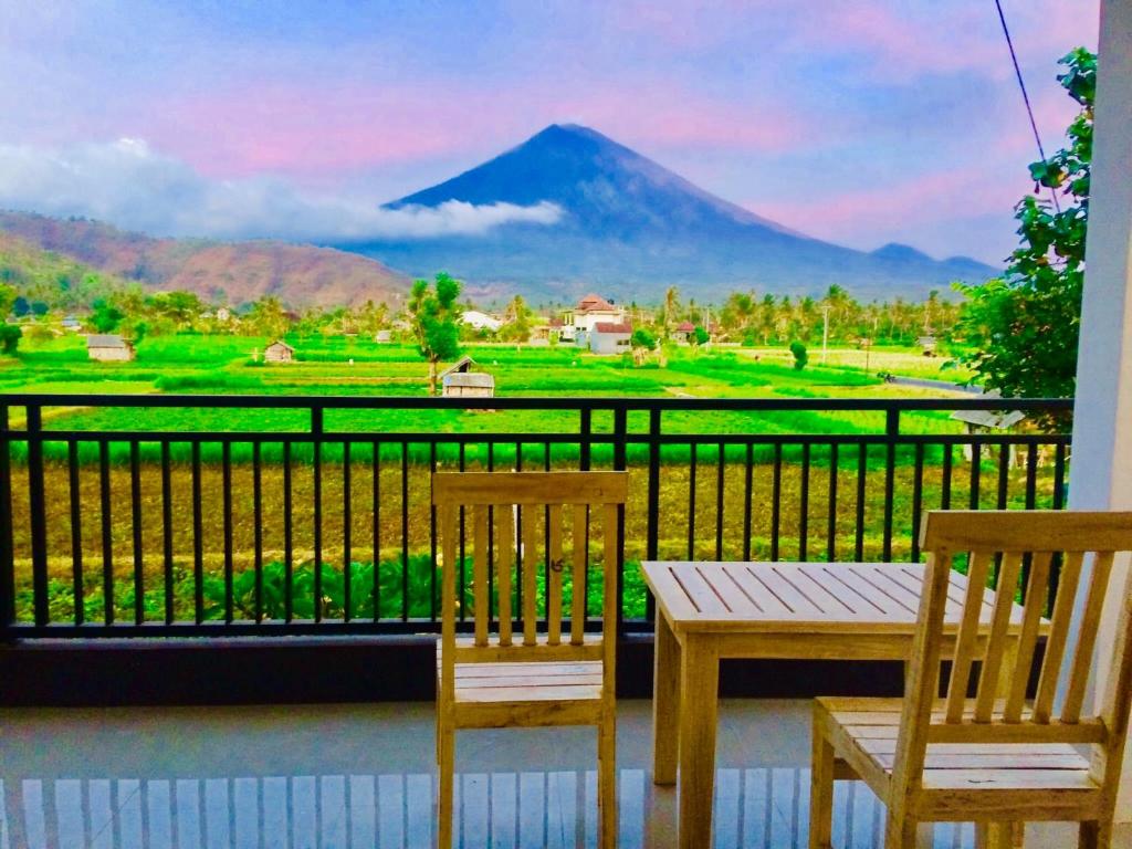 a table and chairs on a balcony with a view of a mountain at D'uma Amed Homestay in Amed