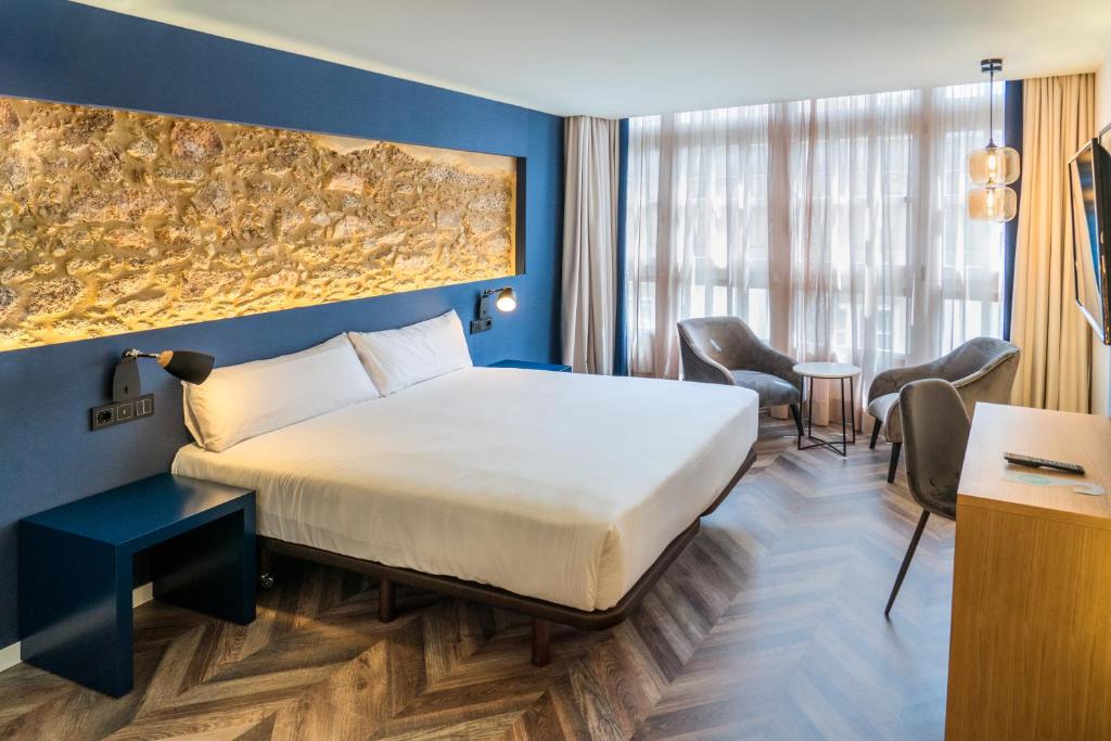 a hotel room with a large bed and chairs at Alda Galería Coruña in A Coruña