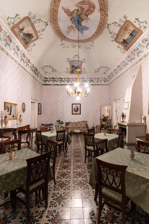 a dining room with tables and chairs and a chandelier at Palazzo Il Cavaliere B&B De Charme in Modica