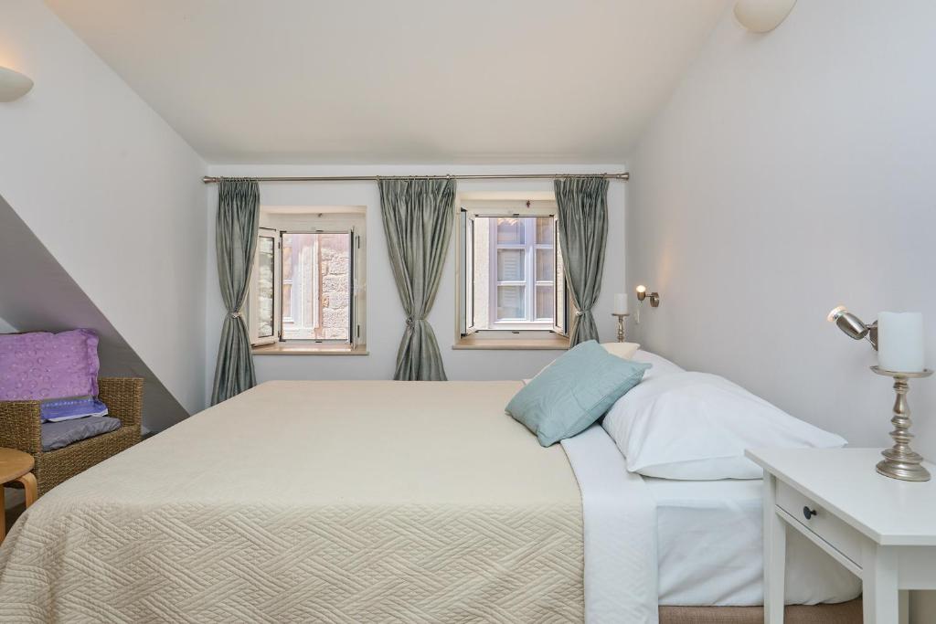 een slaapkamer met een wit bed en 2 ramen bij Room Annette in Dubrovnik