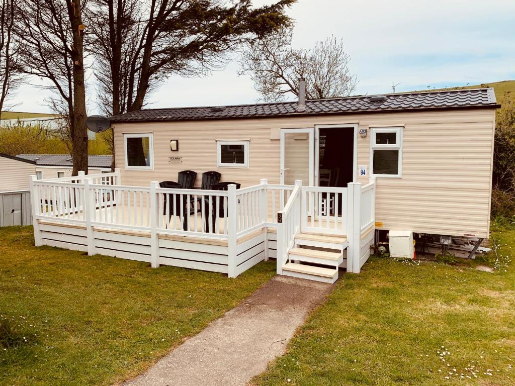 94 Newquay Bay Resort pet friendly في نيوكواي: منزل متنقل أبيض مع شرفة ودرج