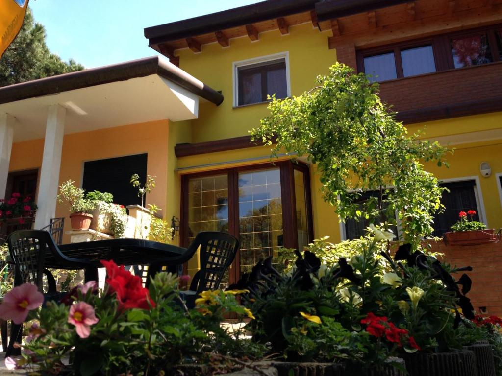 a yellow house with a table and chairs and flowers at Villa orchidea in Rosolina Mare