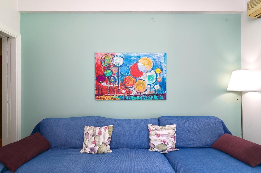een blauwe bank met twee kussens en een schilderij aan de muur bij Venias Two-Bedroom apartment Kallimarmaro and Zappeio area in Athene