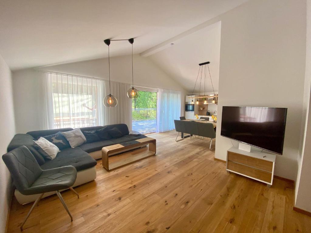 uma sala de estar com um sofá azul e uma televisão de ecrã plano em Zirbenblick Apartment Turrach em Brandstätter