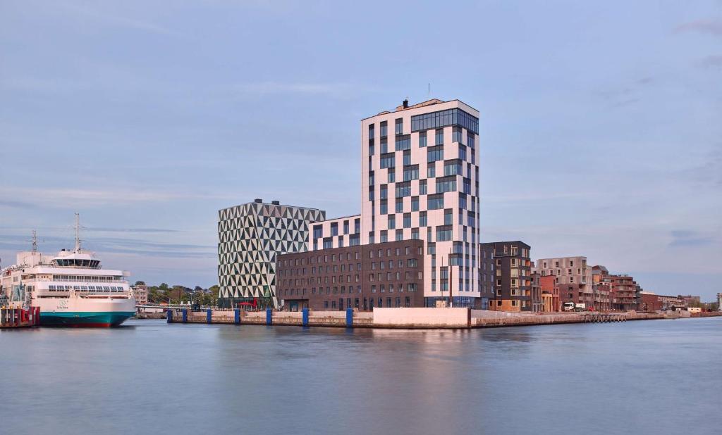 a tall building next to a river with a cruise ship at Scandic Oceanhamnen in Helsingborg