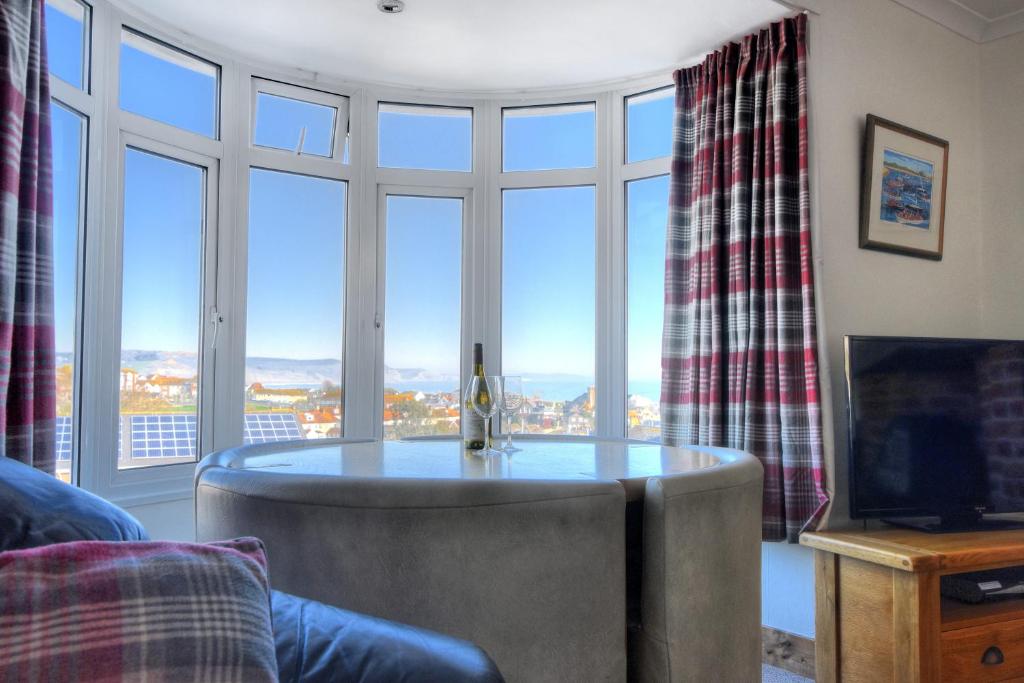 ein Wohnzimmer mit einem Tisch und großen Fenstern in der Unterkunft Seaview in Lyme Regis
