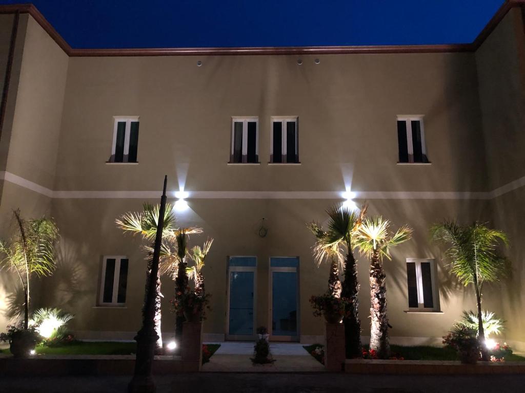 un edificio con palmeras delante de él por la noche en Stellaris en Siderno Marina