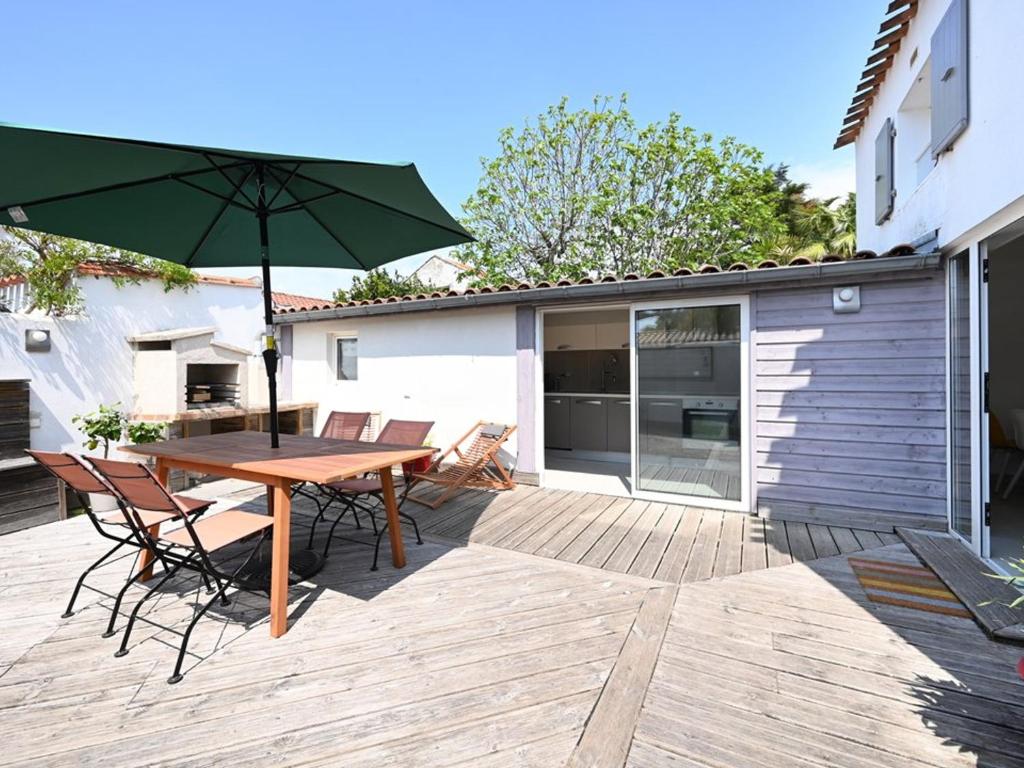 a patio with a wooden table and chairs and an umbrella at Maison Saint-Clément-des-Baleines, 3 pièces, 4 personnes - FR-1-434-95 in Saint-Clément-des-Baleines