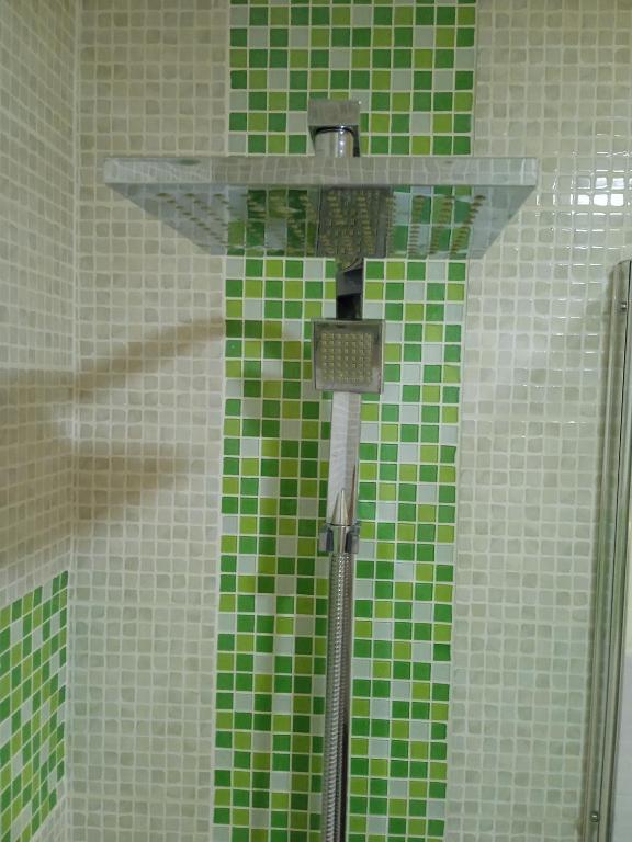 La salle de bains est pourvue d'une douche carrelée de couleur verte et d'une étagère en verre. dans l'établissement Studio proche gare centre ville, à Pau