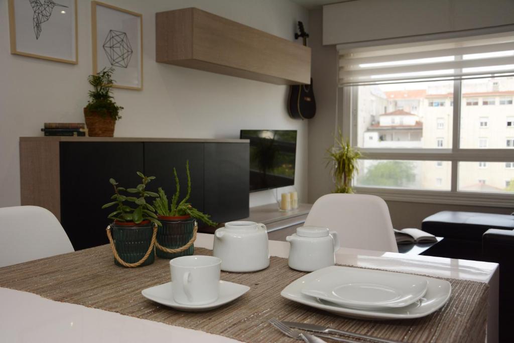 una mesa de comedor con platos blancos. en Oliva Suite, en Pontevedra