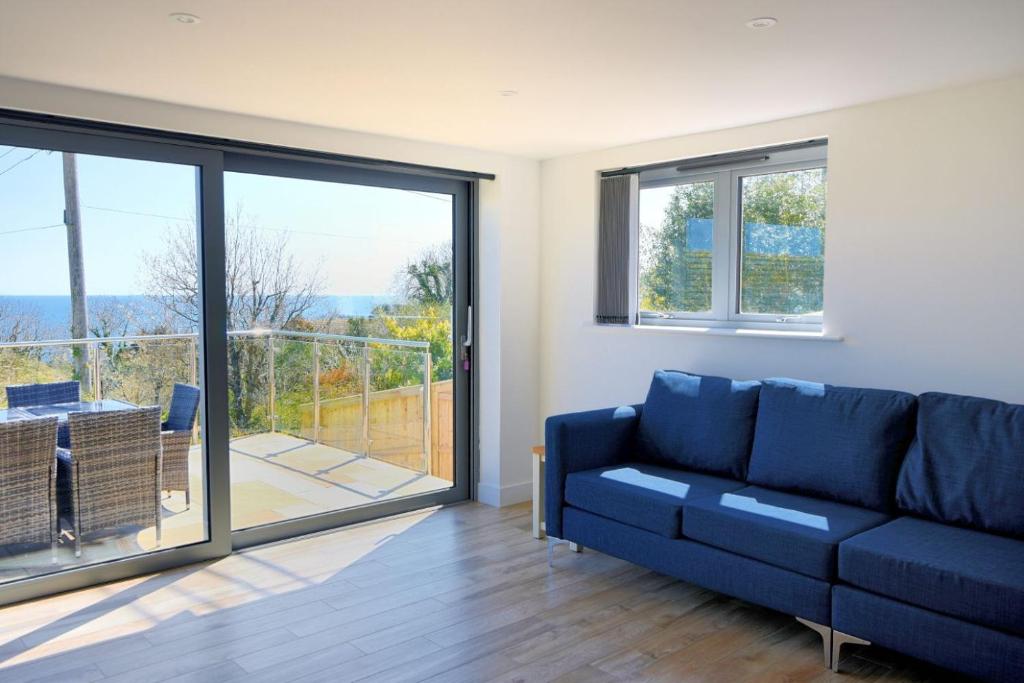 a living room with a blue couch and a balcony at Yarrow in Charmouth