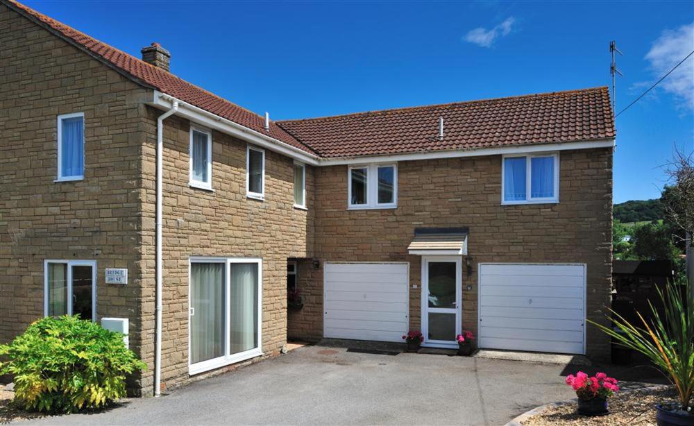 a brick house with two white garage doors at Bridge House Apartment in Charmouth