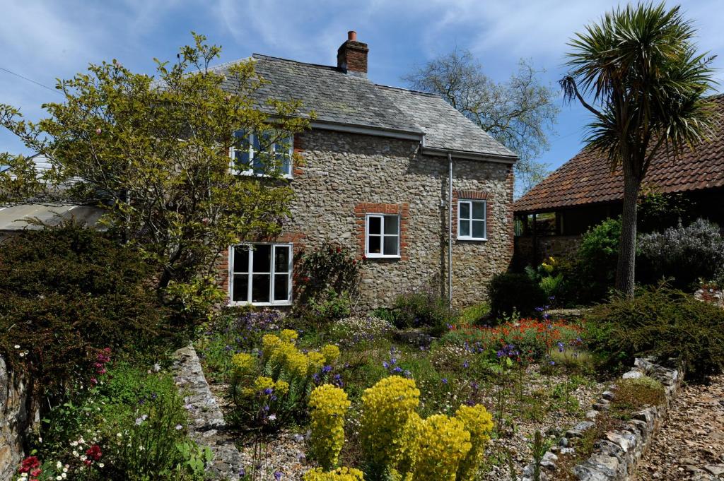 a stone house with a garden in front of it at Trill Cottage in Musbury