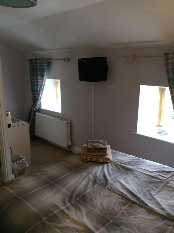 a room with a bed and a television and two windows at The Lord Nelson Inn B&B in Langho