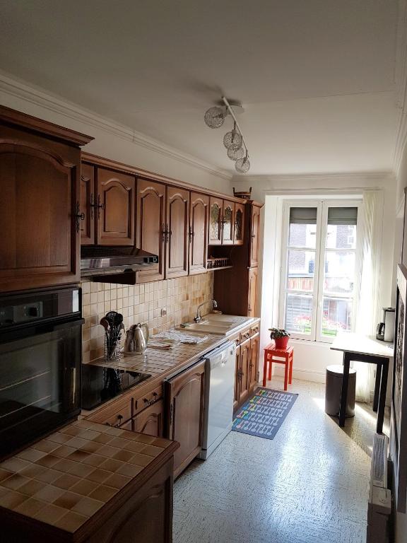 une grande cuisine avec des placards en bois et une fenêtre dans l'établissement Appartement cosy à Langogne 65 m² avec jardin terrasse, à Langogne