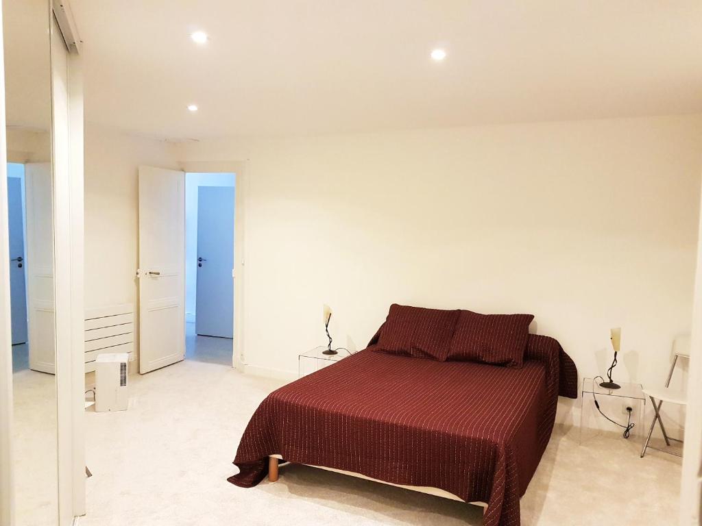 1 dormitorio con 1 cama roja en una habitación blanca en Appartement d'une chambre avec vue sur la ville et jardin a Langogne, en Langogne