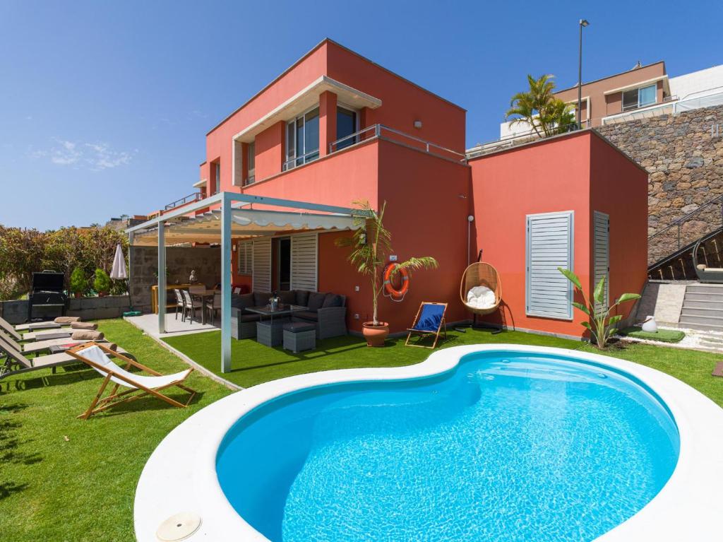a villa with a swimming pool in front of a house at Vista Golf 20 by VillaGranCanaria in Maspalomas