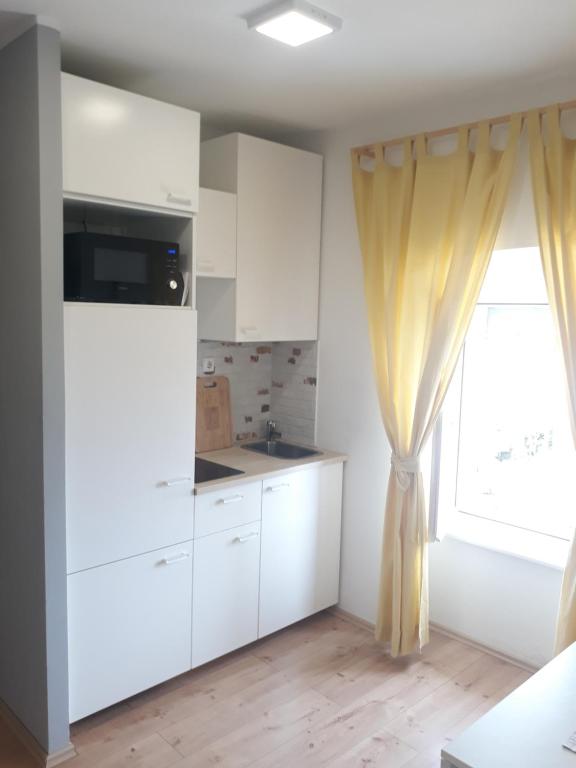 uma cozinha com armários brancos e uma janela em Studio Apartman ''Nicole'' em Pula