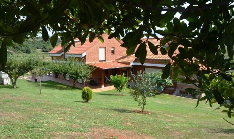 una casa con un patio con árboles delante de ella en Hospedería El Cantio, en Oreña